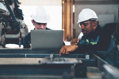 Fabrika işçileri bir atölyede uzman robot kolla çalışıyorlar. Otomatik üretim teknolojisi için endüstriyel robot programlama yazılımı .