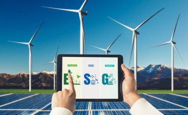 Çevre tasarrufu ve ESG iş konsepti için yeşil iş dönüşümü. İşadamı, çevre dostu yönetime ve alternatif temiz enerji kullanımına yönelik kurumsal bir hedef belirlemek için tablet kullanıyor.