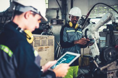 Fabrika işçileri bir atölyede uzman robot kolla çalışıyorlar. Otomatik üretim teknolojisi için endüstriyel robot programlama yazılımı .