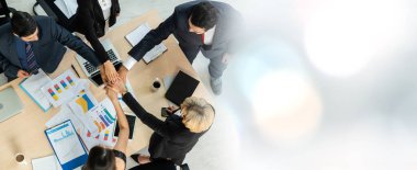 Mutlu iş adamları takım çalışmasının başarısını geniş görüşle kutlarken ofis masasındaki neşe yukarıdan çekiliyor. Genç işadamı ve işkadını işçiler neşeli bir zafer kazandılar. .