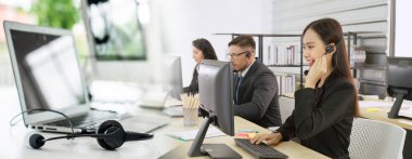 Ofiste çalışan kulaklık takan işadamları uzak müşteri ya da meslektaşlarını desteklemek için çalışıyorlar. Çağrı merkezi, tele pazarlama, müşteri destek acentesi geniş görünümde hizmet sunar .