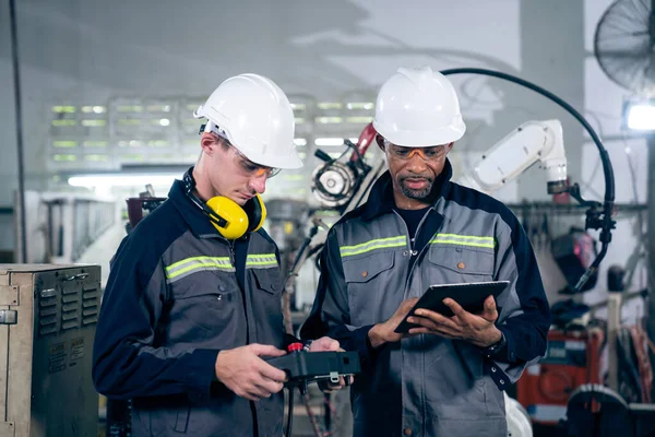 Group of factory job workers using adept machine equipment in a workshop . Industry manufacturing and engineering technology concept .