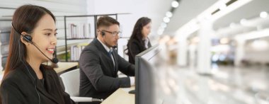 Ofiste çalışan kulaklık takan işadamları uzak müşteri ya da meslektaşlarını desteklemek için çalışıyorlar. Çağrı merkezi, tele pazarlama, müşteri destek acentesi geniş görünümde hizmet sunar .