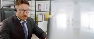 Ofiste çalışan kulaklık takan işadamları uzak müşteri ya da meslektaşlarını desteklemek için çalışıyorlar. Çağrı merkezi, tele pazarlama, müşteri destek acentesi geniş görünümde hizmet sunar .