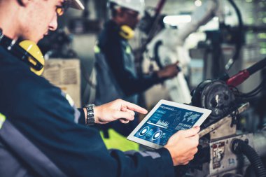 Fabrika işçileri bir atölyede uzman robot kolla çalışıyorlar. Otomatik üretim teknolojisi için endüstriyel robot programlama yazılımı .