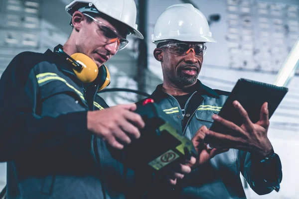 Group of factory job workers using adept machine equipment in a workshop . Industry manufacturing and engineering technology concept .