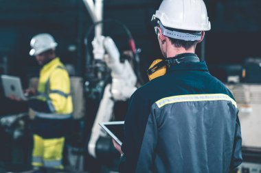 Fabrika işçileri bir atölyede uzman robot kolla çalışıyorlar. Otomatik üretim teknolojisi için endüstriyel robot programlama yazılımı .