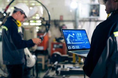 Fabrika işçileri bir atölyede uzman robot kolla çalışıyorlar. Otomatik üretim teknolojisi için endüstriyel robot programlama yazılımı .