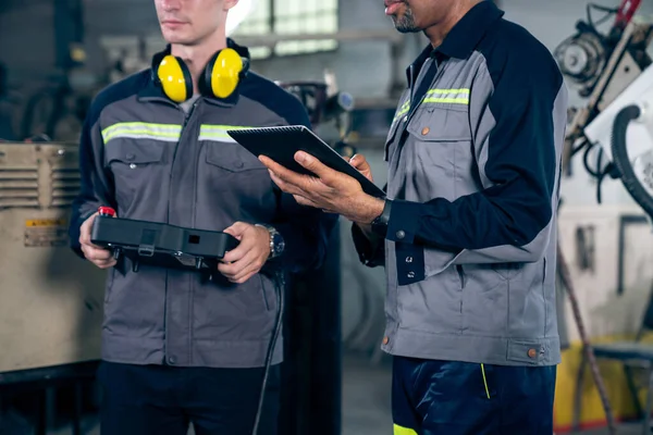 Group of factory job workers using adept machine equipment in a workshop . Industry manufacturing and engineering technology concept .