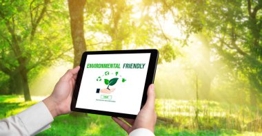 Çevre tasarrufu ve ESG iş konsepti için yeşil iş dönüşümü. İşadamı, çevre dostu yönetime ve alternatif temiz enerji kullanımına yönelik kurumsal bir hedef belirlemek için tablet kullanıyor.