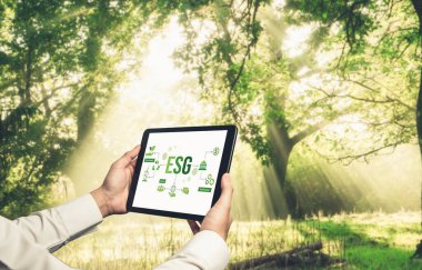 Çevre tasarrufu ve ESG iş konsepti için yeşil iş dönüşümü. İşadamı, çevre dostu yönetime ve alternatif temiz enerji kullanımına yönelik kurumsal bir hedef belirlemek için tablet kullanıyor.