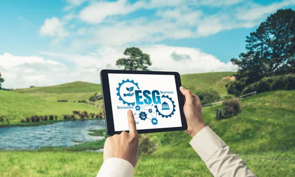 Green business transformation for environment saving and ESG business concept. Businessman using tablet to set corporate goal toward environmental friendly management and alternative clean energy use.