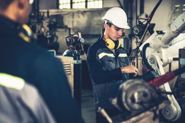 Fabrika işçileri bir atölyede uzman robot kolla çalışıyorlar. Otomatik üretim teknolojisi için endüstriyel robot programlama yazılımı .