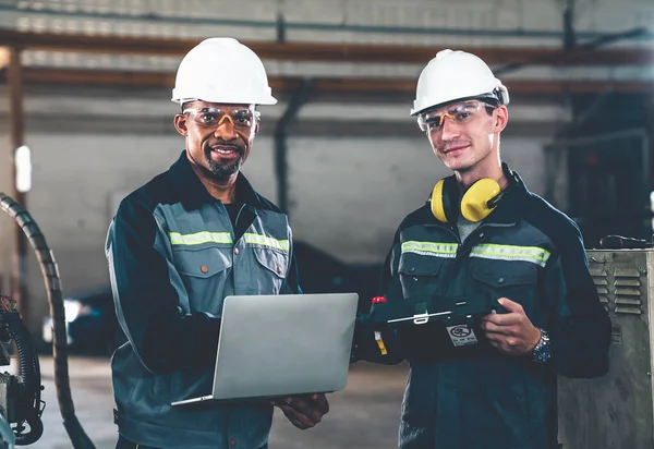 Two factory workers using adept machine equipment in a workshop . Industry manufacturing and engineering technology concept .