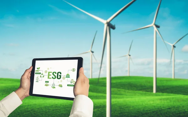 Green business transformation for environment saving and ESG business concept. Businessman using tablet to set corporate goal toward environmental friendly management and alternative clean energy use.