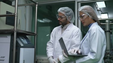 Kimyasal ve biyomedikal deney laboratuarında çalışan profesyonel üniformalı iki bilim adamı.