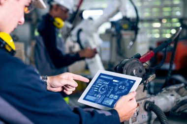 Fabrika işçileri bir atölyede uzman robot kolla çalışıyorlar. Otomatik üretim teknolojisi için endüstriyel robot programlama yazılımı .