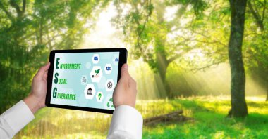 Çevre tasarrufu ve ESG iş konsepti için yeşil iş dönüşümü. İşadamı, çevre dostu yönetime ve alternatif temiz enerji kullanımına yönelik kurumsal bir hedef belirlemek için tablet kullanıyor.