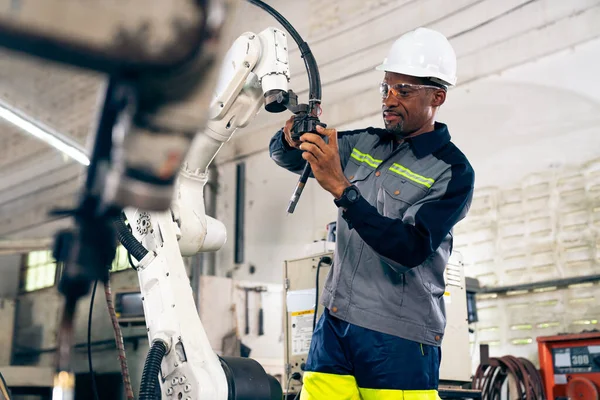 African American factory worker working with adept robotic arm in a workshop . Industry robot programming software for automated manufacturing technology .