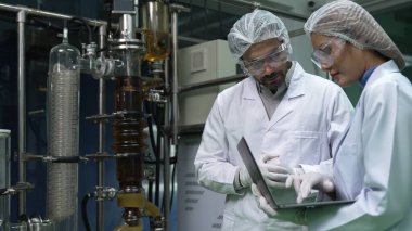 Kimyasal ve biyomedikal deney laboratuarında çalışan profesyonel üniformalı iki bilim adamı.