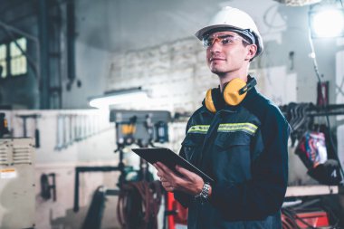 Bir atölye binasında usta tablet bilgisayar kullanan genç bir fabrika işçisi. Endüstriyel teknoloji ve imalat yazılım yapılandırması .