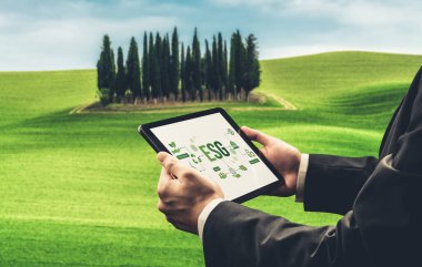 Çevre tasarrufu ve ESG iş konsepti için yeşil iş dönüşümü. İşadamı, çevre dostu yönetime ve alternatif temiz enerji kullanımına yönelik kurumsal bir hedef belirlemek için tablet kullanıyor.