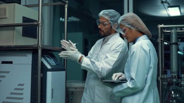 Kimyasal ve biyomedikal deney laboratuarında çalışan profesyonel üniformalı iki bilim adamı.