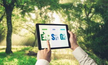 Çevre tasarrufu ve ESG iş konsepti için yeşil iş dönüşümü. İşadamı, çevre dostu yönetime ve alternatif temiz enerji kullanımına yönelik kurumsal bir hedef belirlemek için tablet kullanıyor.