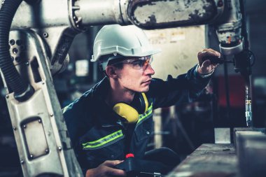 Bir atölyede usta bir robot kolla çalışan genç bir fabrika işçisi. Otomatik üretim teknolojisi için endüstriyel robot programlama yazılımı .