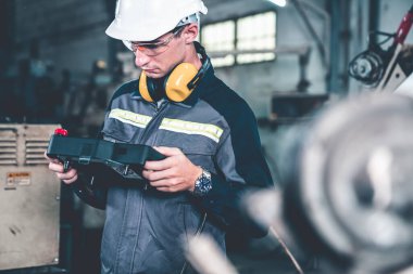 Bir atölyede usta bir robot kolla çalışan genç bir fabrika işçisi. Otomatik üretim teknolojisi için endüstriyel robot programlama yazılımı .