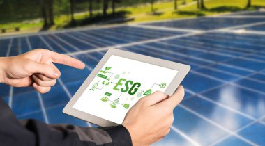 Çevre tasarrufu ve ESG iş konsepti için yeşil iş dönüşümü. İşadamı, çevre dostu yönetime ve alternatif temiz enerji kullanımına yönelik kurumsal bir hedef belirlemek için tablet kullanıyor.