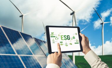 Çevre tasarrufu ve ESG iş konsepti için yeşil iş dönüşümü. İşadamı, çevre dostu yönetime ve alternatif temiz enerji kullanımına yönelik kurumsal bir hedef belirlemek için tablet kullanıyor.