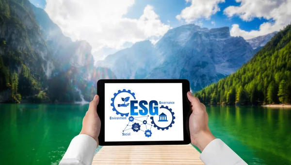 Green business transformation for environment saving and ESG business concept. Businessman using tablet to set corporate goal toward environmental friendly management and alternative clean energy use.