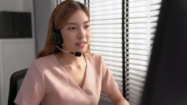 Competent female operator working on computer and while talking with clients. Concept relevant to both call centers and customer service offices.
