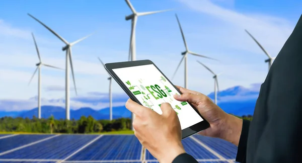 Green business transformation for environment saving and ESG business concept. Businessman using tablet to set corporate goal toward environmental friendly management and alternative clean energy use.