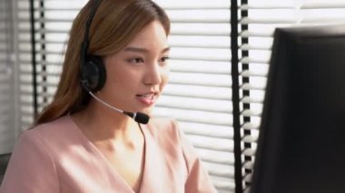 Competent female operator working on computer and while talking with clients. Concept relevant to both call centers and customer service offices.