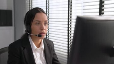 Competent african american female operator working on computer and while talking with clients. Concept relevant to both call centers and customer service offices.