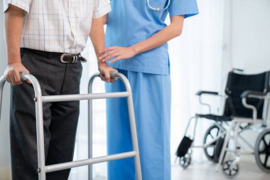 Physiotherapist assists her contented senior patient on folding walker. Recuperation for elderly, seniors care, nursing home.
