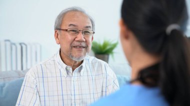 A young female doctor inquires about personal information of a contented senior at home. Medical care for the elderly, elderly illness, and nursing homes, home care.
