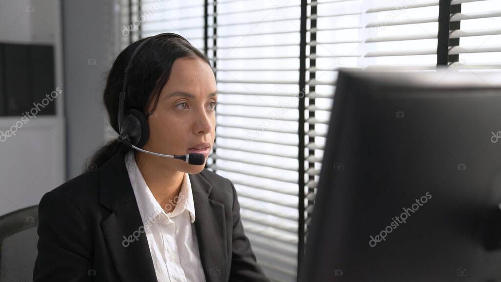 Competent female operator working on computer and talking with clients. Concept relevant to both call centers and customer service offices.