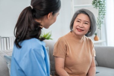 A contented senior woman visited by her personal caregiver and hold each others hands.
