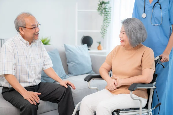 A contented senior couple and their in-home nurse. Elderly female in wheelchair with her young caregiver.