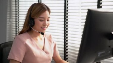 Competent female operator working on computer and while talking with clients. Concept relevant to both call centers and customer service offices.