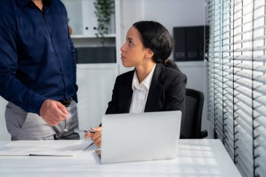 Competent female employee discussing with her colleague, employer using laptop at her office. Interpersonal relations among coworkers.