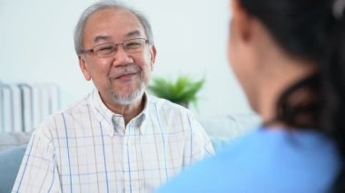A young female doctor inquires about personal information of a contented senior at home. Medical care for the elderly, elderly illness, and nursing homes, home care.
