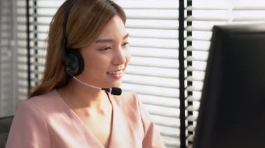 Competent female operator working on computer and while talking with clients. Concept relevant to both call centers and customer service offices.
