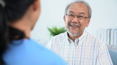 A young female doctor inquires about personal information of a contented senior at home. Medical care for the elderly, elderly illness, and nursing homes, home care.