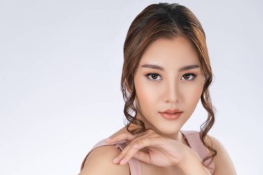 Close up gorgeous young girl posing beauty gesture with healthy clear skin and soft makeup. Cosmetology and beauty concept.