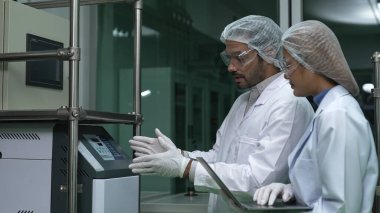 Kimyasal ve biyomedikal deney laboratuarında çalışan profesyonel üniformalı iki bilim adamı.