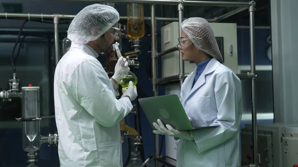 Kimyasal ve biyomedikal deney laboratuarında çalışan profesyonel üniformalı iki bilim adamı.